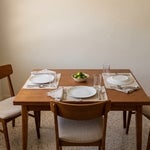 Dining table in a Fort Myers bungalow set for one, with a second place laid and its plate turned face down, representing a Florida Lady Bird deed that names a beneficiary now but transfers the home only at death