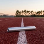 Blank relay baton on the lane line of an empty Cape Coral running track at dawn, representing a Florida successor trustee taking over trust administration after a death