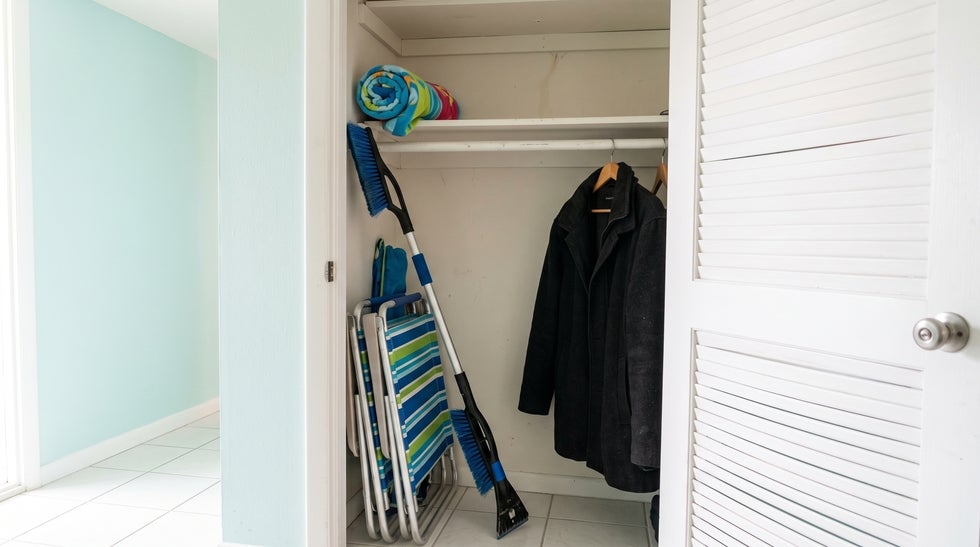 Snow brush and wool coat hanging beside beach chairs in a Fort Myers Beach condo closet, representing Florida property owned by someone who lives in another state