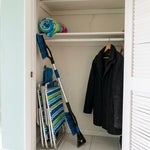 Snow brush and wool coat hanging beside beach chairs in a Fort Myers Beach condo closet, representing Florida property owned by someone who lives in another state