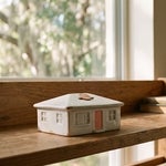 A house-shaped coin bank with a coin on its roof on a Punta Gorda bookshelf, representing an inherited Florida home that still carries a mortgage