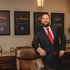 Joshua Wilson, family law attorney in Cass County, Missouri, standing confidently in his Raymore office in a navy suit and red tie