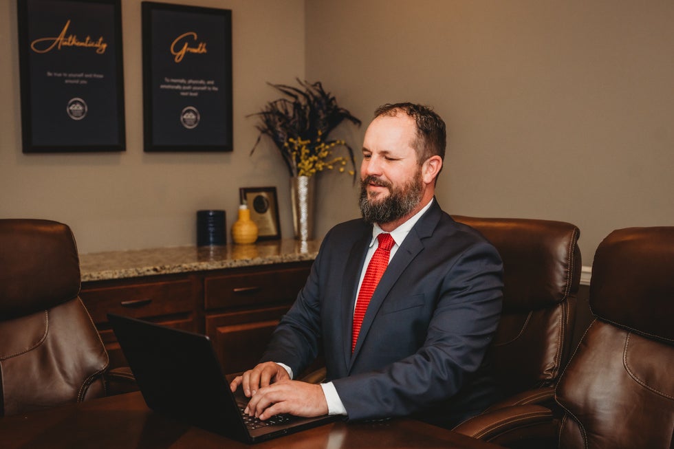 Joshua Wilson, family law attorney in Cass County, Missouri, standing confidently in his Raymore office in a navy suit and red tie