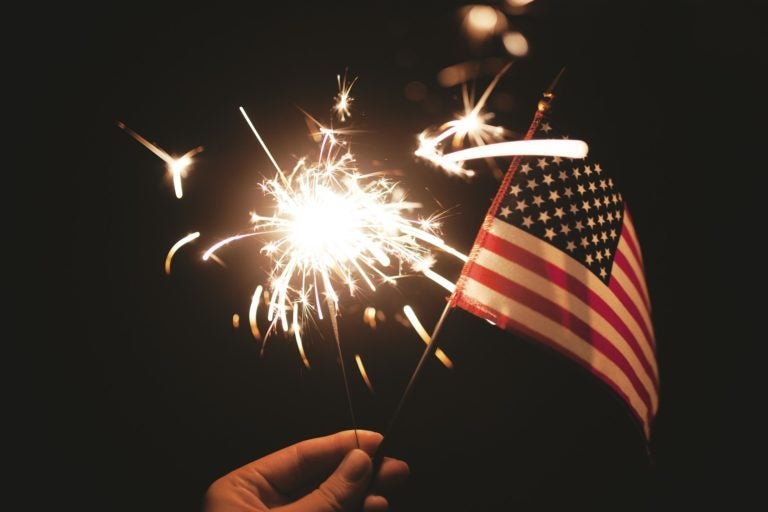 Hand holding a sparkler and small American flag.