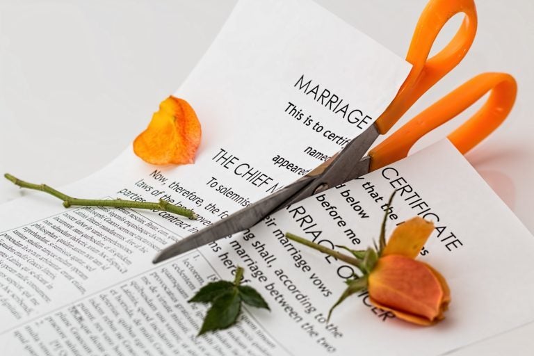 Scissors cutting a marriage certificate paper and flower