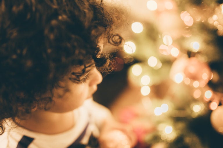 Child standing next to a Christmas tree