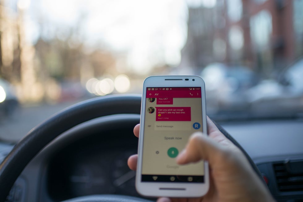 Person using cell phone to text while driving