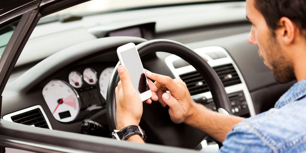 Man driving a car while using his phone