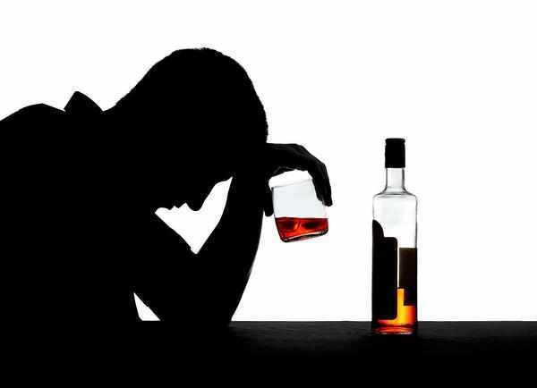 Man slumped over holding alcohol next to alcohol bottle