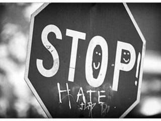 Stop sign vandalized with the word hate underneath the word stop.